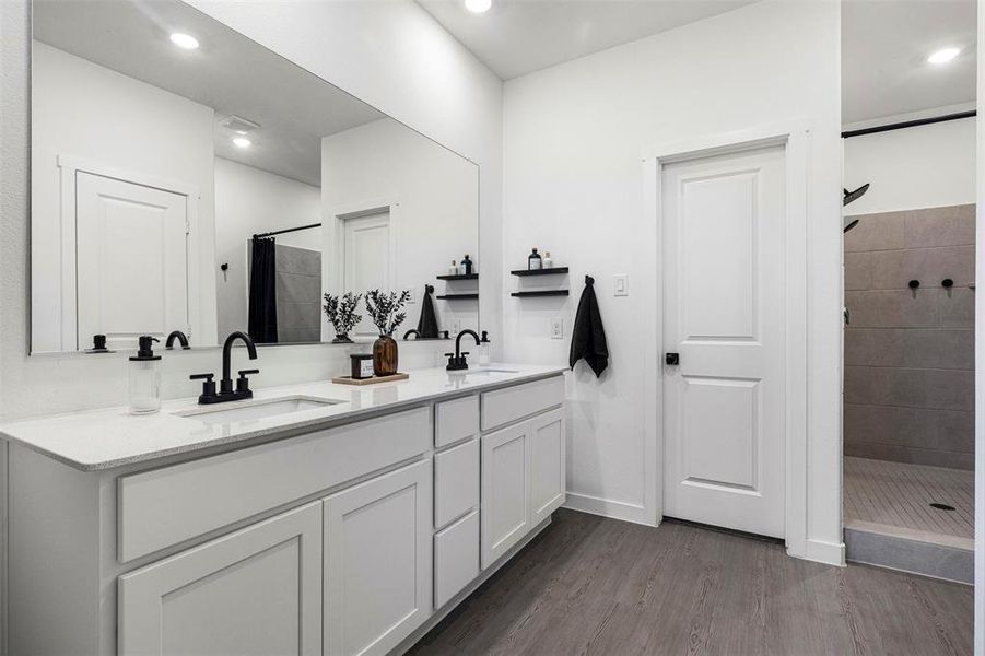Double vanity with white cabinetry and quartz countertops, featuring matte black faucets and a full-width mirror Double vanity with white cabinetry and quartz countertops, featuring matte black faucets and a full-width mirror