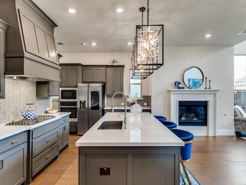 Kitchen featuring gray cabinets, appliances with stainless steel finishes, light countertops, custom exhaust hood, and recessed lighting