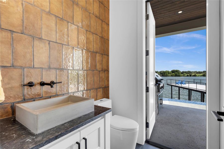 Half bathroom with vanity, a water view, and tile walls