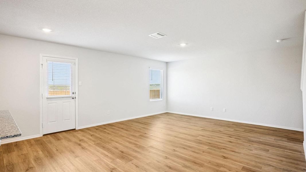 Spacious room featuring wood-finish flooring, recessed lighting, and bright white walls