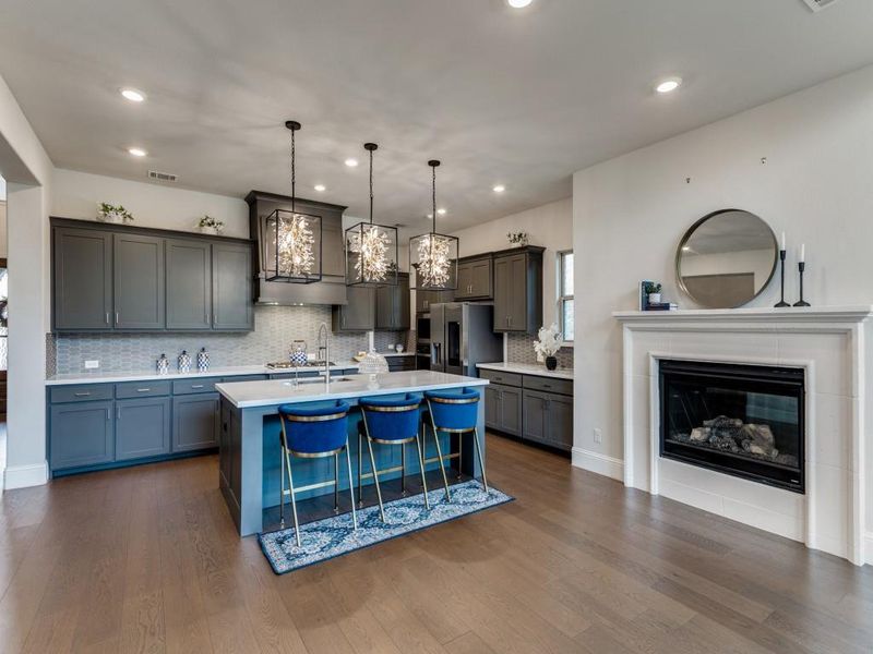 Kitchen featuring light countertops, dark wood finished floors, pendant lighting, tasteful backsplash, and stainless steel fridge