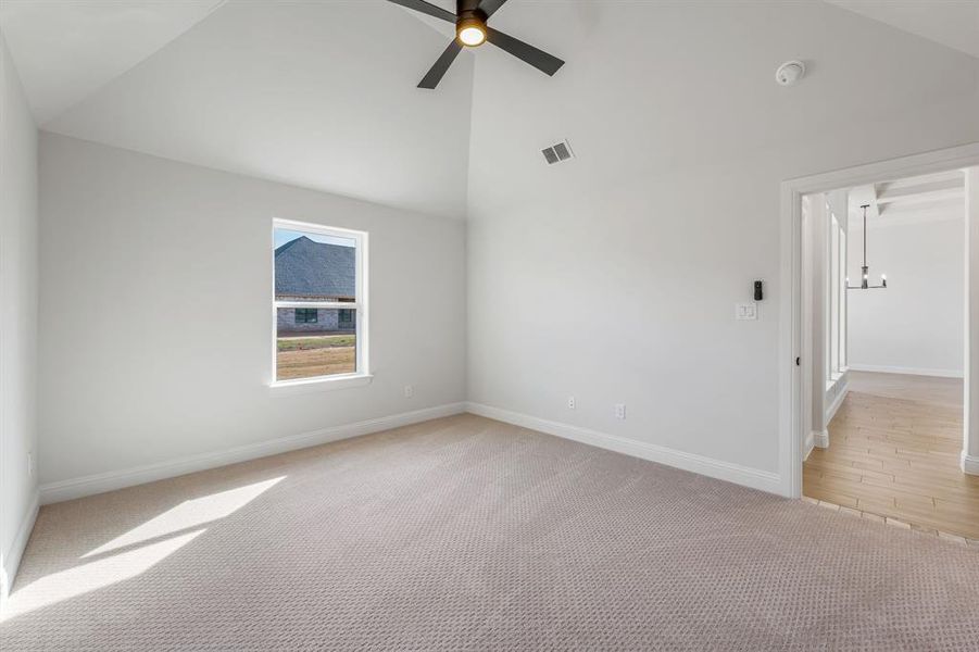 Unfurnished room featuring ceiling fan, lofted ceiling, and light colored carpet