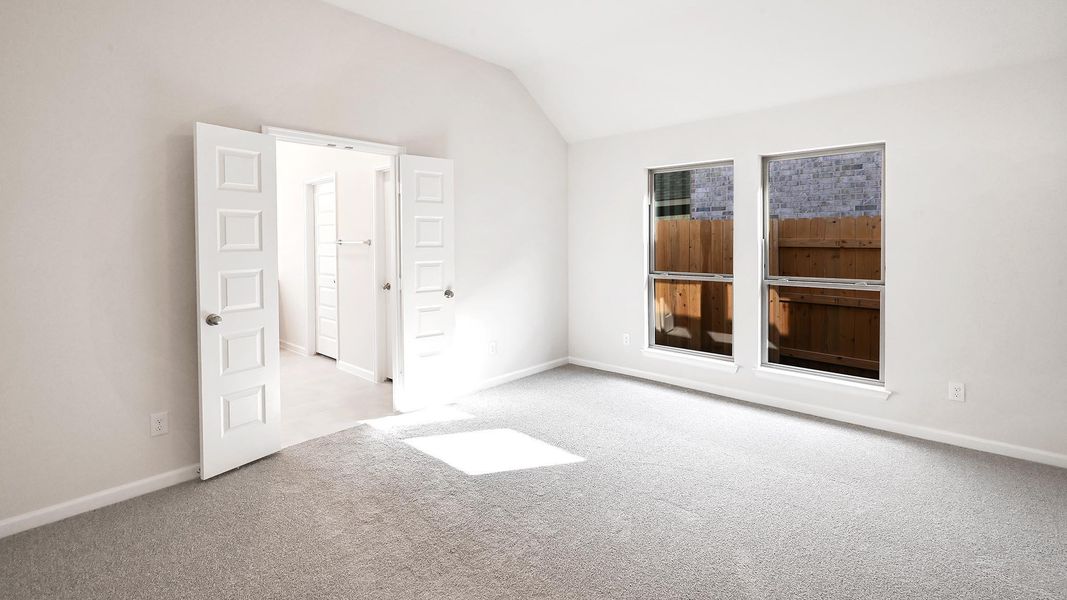 Empty room featuring light carpet and lofted ceiling