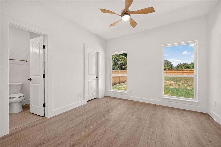 Spacious room featuring wood-finish flooring, white walls, and a modern ceiling fan with light fixture
