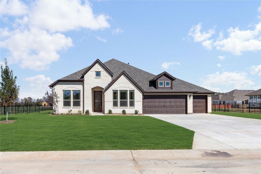 Single-story home with white brick exterior, arched windows, two-car garage, and green front lawn
