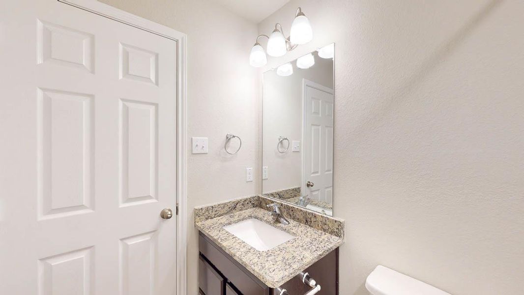 Half bathroom with vanity and a textured wall