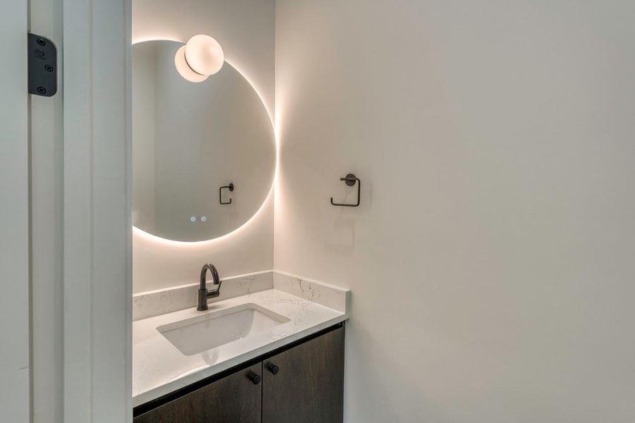Clean lines and a backlit circular mirror define this modern powder room vanity. Clean lines and a backlit circular mirror define this modern powder room vanity.