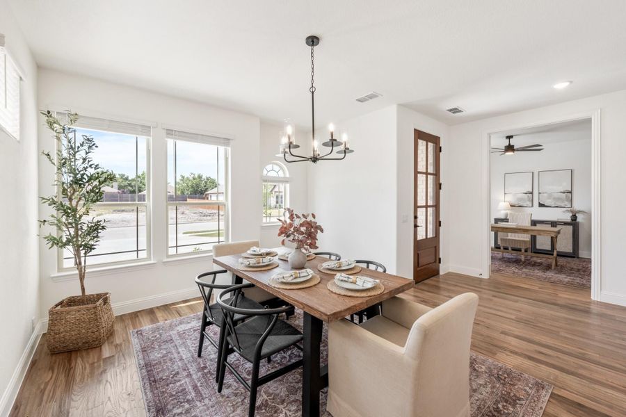 Dining room with wood table, black chairs, chandelier, and hardwood floors near large windows
