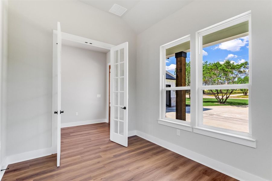 Spare room featuring light wood-type flooring and lofted ceiling