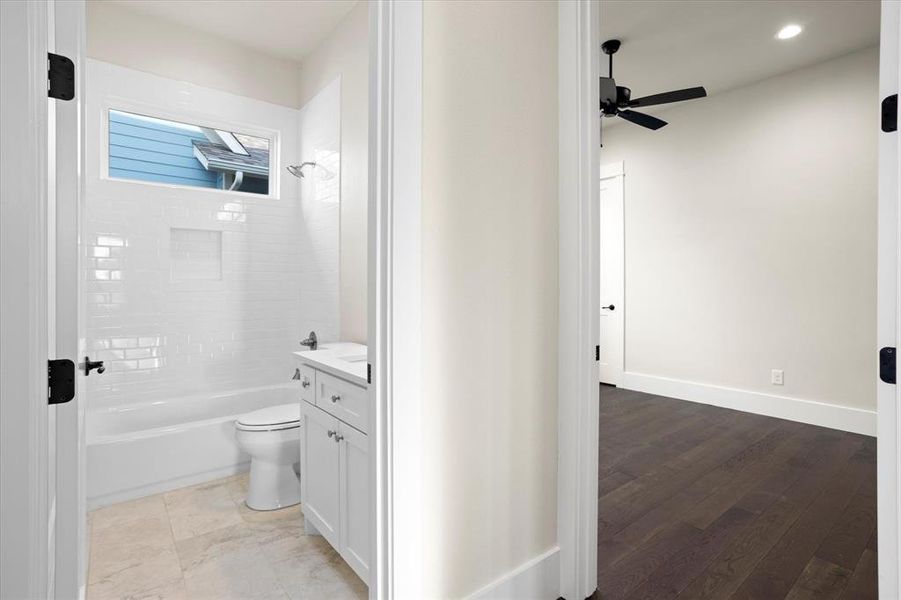 Full bathroom featuring tiled shower / bath, hardwood / wood-style floors, toilet, ceiling fan, and vanity