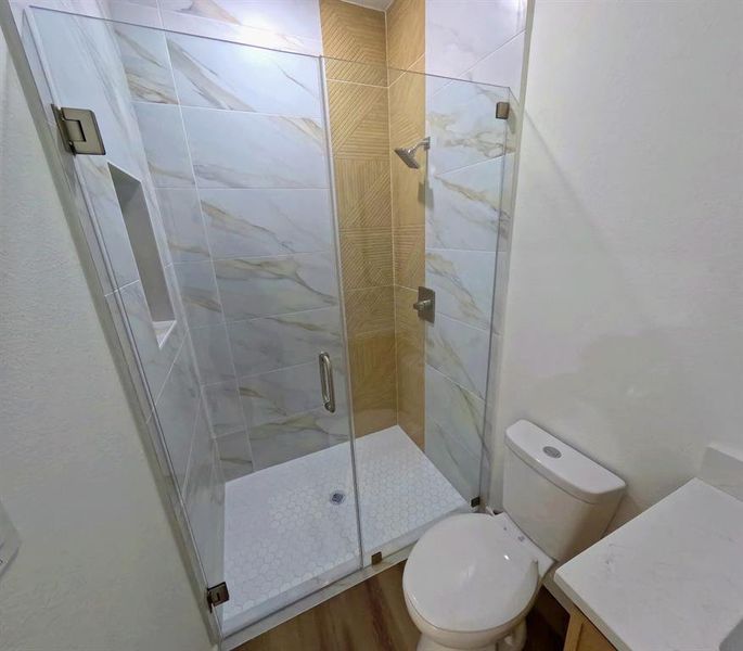 Bathroom featuring vanity, a stall shower, and wood finished floors Bathroom featuring vanity, a stall shower, and wood finished floors