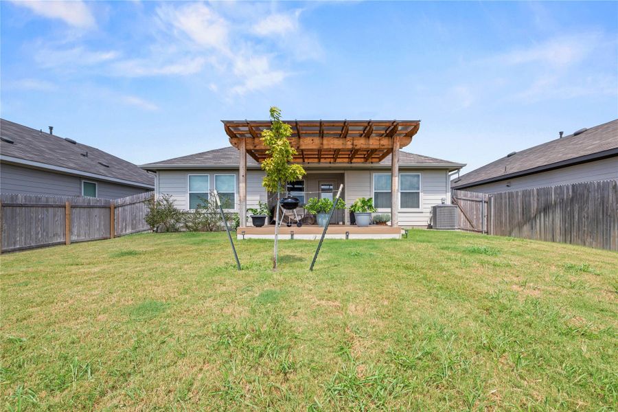 A private backyard oasis features a wooden pergola, ideal for outdoor entertaining and relaxation.
