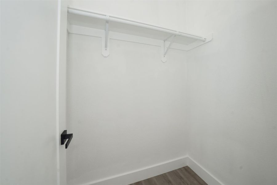 Bright and spacious family room with large windows and a glass-paneled door, allowing plenty of natural light. It features light wooden flooring and a modern, open layout with a glimpse of a stylish kitchen countertop.