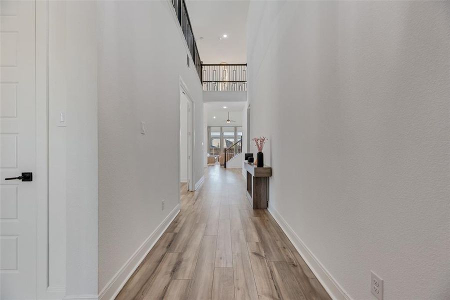Corridor with a towering ceiling, light wood-type flooring, and recessed lighting