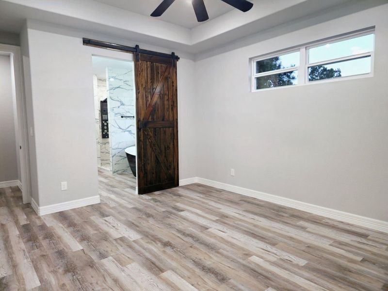 Primary bedroom features a rustic sliding barn door leading to a modern bathroom.