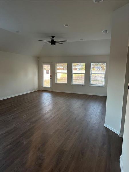 Spare room featuring dark wood-style flooring, plenty of natural light, and ceiling fan