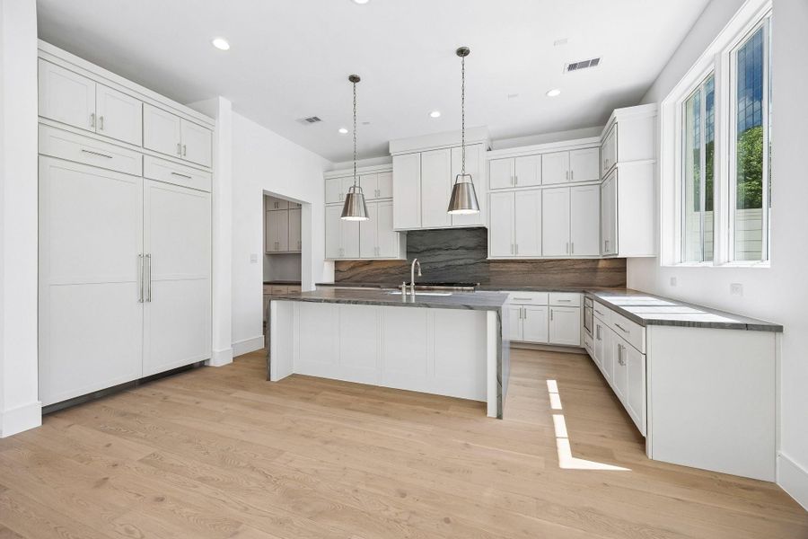 Leathered Blue Tahoe Quartzite waterfall island and undermount Porcelain sink with Kallista faucet complete this luxury kitchen. Ample prep space, storage space, and island seating make this space functional and stunning.