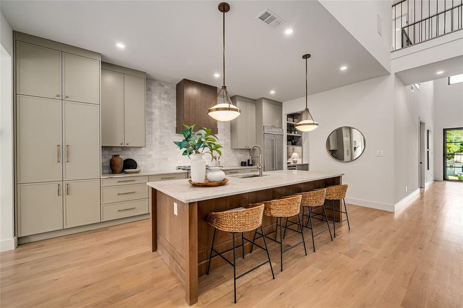 Kitchen with backsplash, pendant lighting, an island with sink, light wood-style floors, and recessed lighting Kitchen with backsplash, pendant lighting, an island with sink, light wood-style floors, and recessed lighting