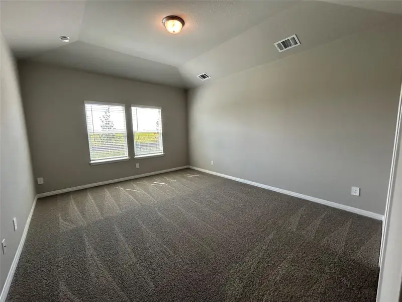 Empty room featuring carpet floors and vaulted ceiling