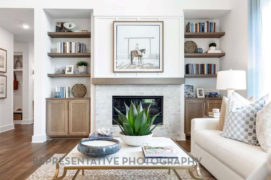 Living room featuring dark wood-style flooring, built in features, and a fireplace Living room featuring dark wood-style flooring, built in features, and a fireplace