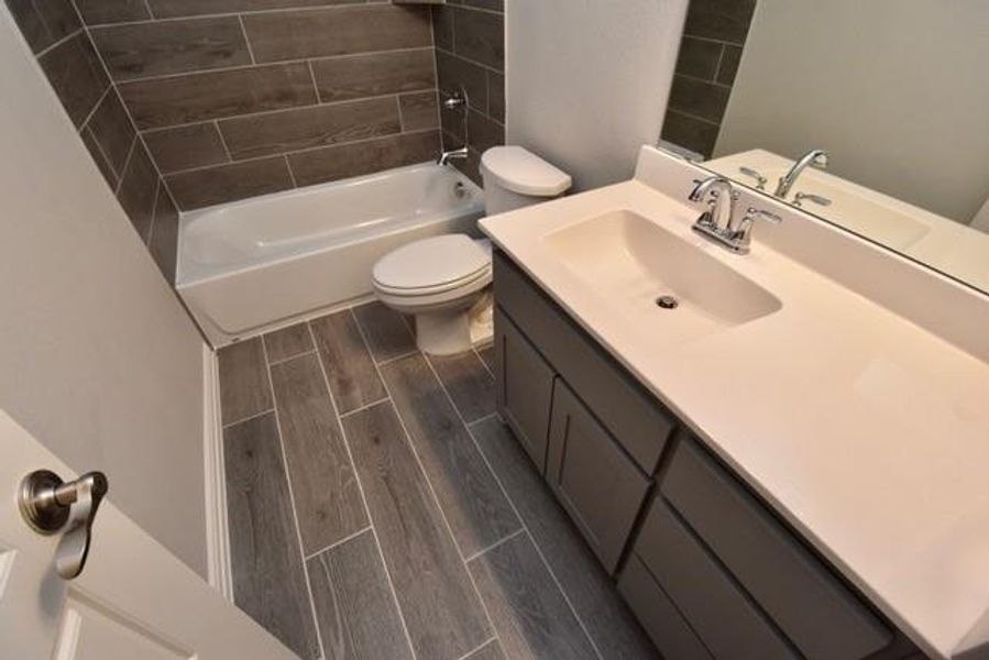 Bathroom with tiled floors, vanity, and shower / tub combination Bathroom with tiled floors, vanity, and shower / tub combination