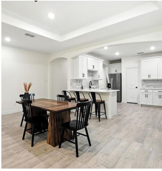 Dining area with recessed lighting, ornamental molding, wood tiled floors, and a tray ceiling