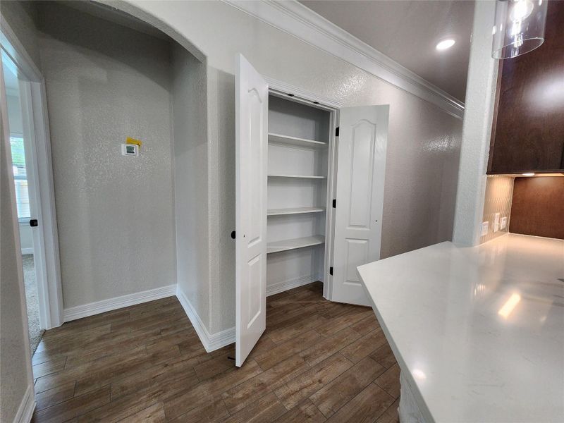 A well-appointed kitchen pantry offers abundant storage with built-in shelving, complemented by rich wood-look flooring. A well-appointed kitchen pantry offers abundant storage with built-in shelving, complemented by rich wood-look flooring.