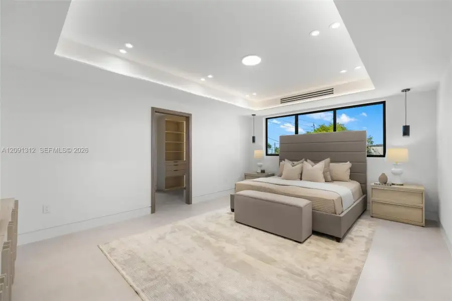 Tray ceiling with recessed ambient lighting, large-format tile flooring, oversized black-frame window, and built-in walk-in closet shelving Tray ceiling with recessed ambient lighting, large-format tile flooring, oversized black-frame window, and built-in walk-in closet shelving