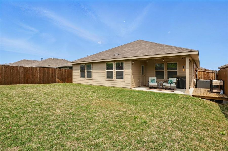 Back of property featuring a fenced backyard, a lawn, and a wooden deck