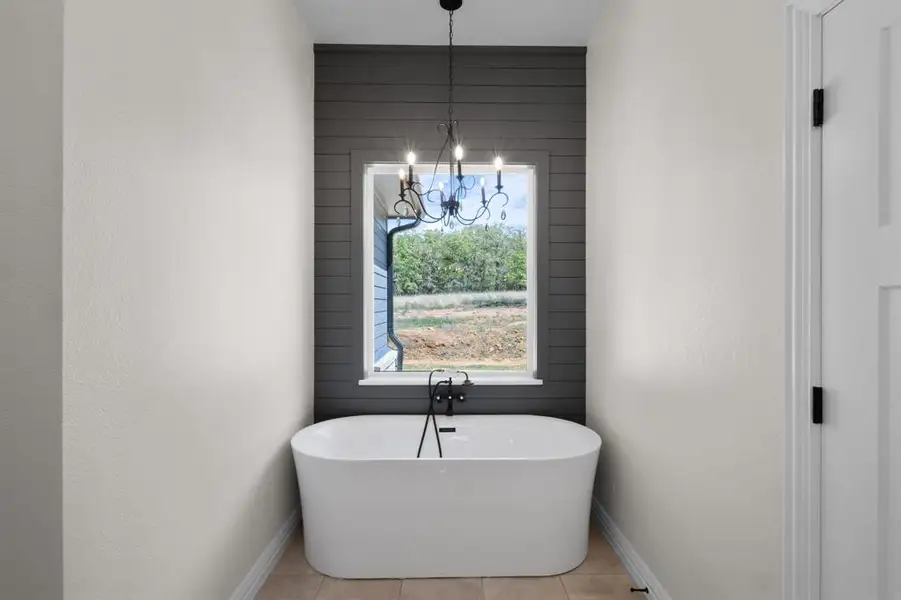 Bathroom with tile patterned floors, baseboards, an inviting chandelier, and a soaking tub