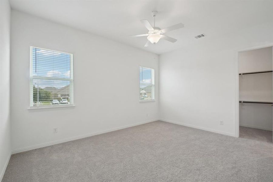 Unfurnished bedroom featuring multiple windows, ceiling fan, a closet, and light carpet