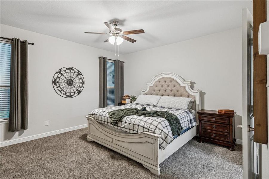 Primary bedroom featuring carpet floors, baseboards, and a ceiling fan Primary bedroom featuring carpet floors, baseboards, and a ceiling fan