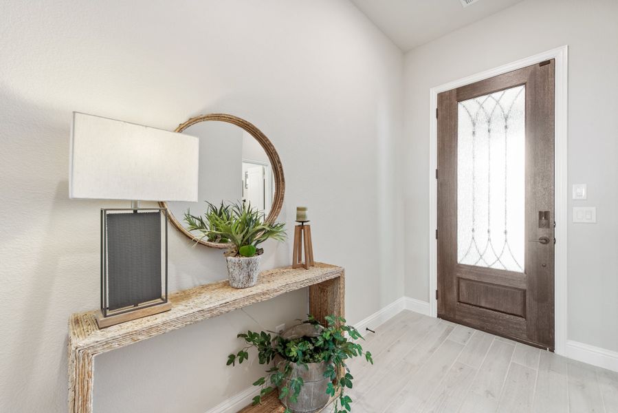 Entryway with wood front door, glass panel, console table, round mirror, and light hardwood floors Entryway with wood front door, glass panel, console table, round mirror, and light hardwood floors
