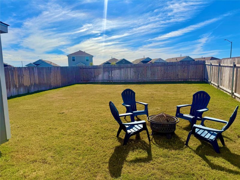Fenced backyard featuring a fire pit and a residential view