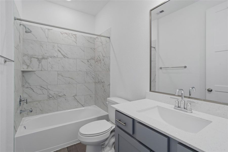 A streamlined secondary bathroom providing a functional tub/shower combination, double sinks, and modern fixtures, seamlessly blending practicality and style. A streamlined secondary bathroom providing a functional tub/shower combination, double sinks, and modern fixtures, seamlessly blending practicality and style.