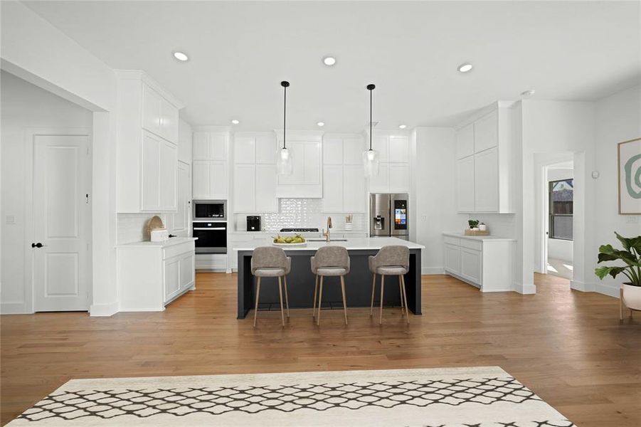 Kitchen with a kitchen breakfast bar, tasteful backsplash, a kitchen island with sink, white cabinetry, and stainless steel appliances Kitchen with a kitchen breakfast bar, tasteful backsplash, a kitchen island with sink, white cabinetry, and stainless steel appliances