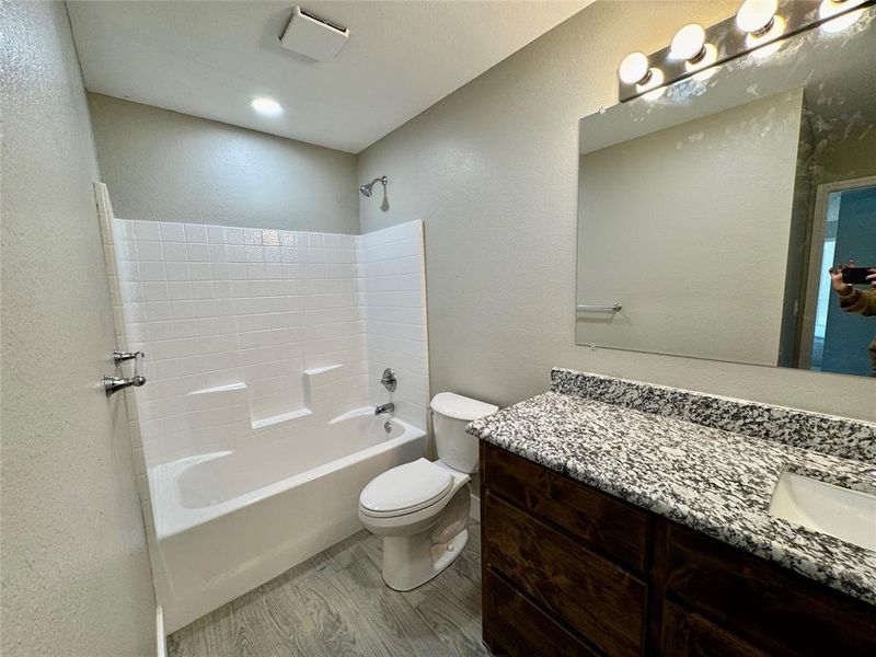 Bathroom featuring a textured wall, washtub / shower combination, and vanity Bathroom featuring a textured wall, washtub / shower combination, and vanity