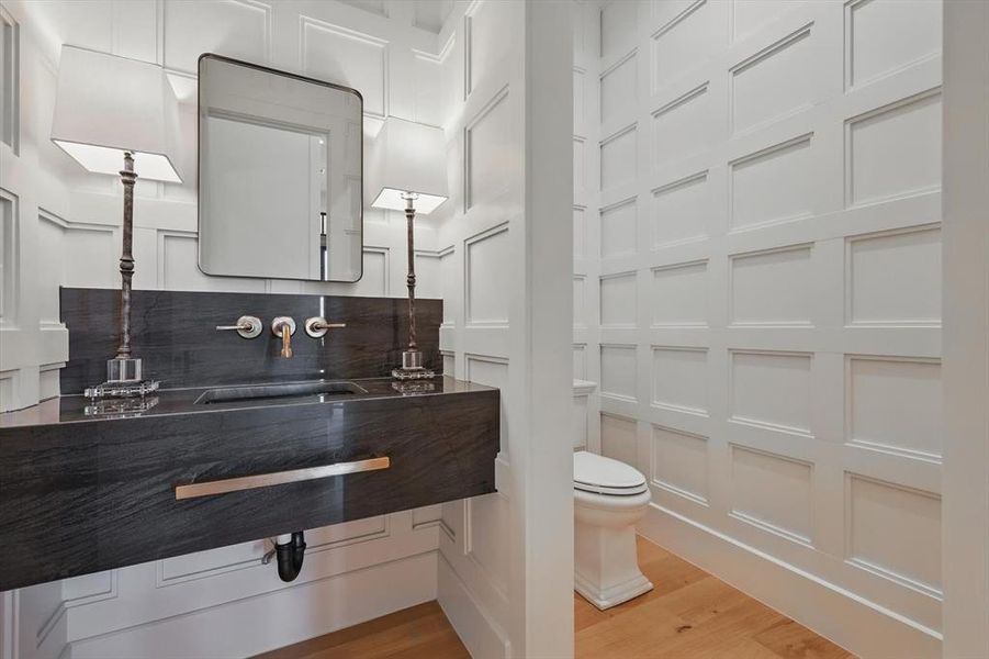 Bathroom featuring wood finished floors, vanity, and a decorative wall Bathroom featuring wood finished floors, vanity, and a decorative wall