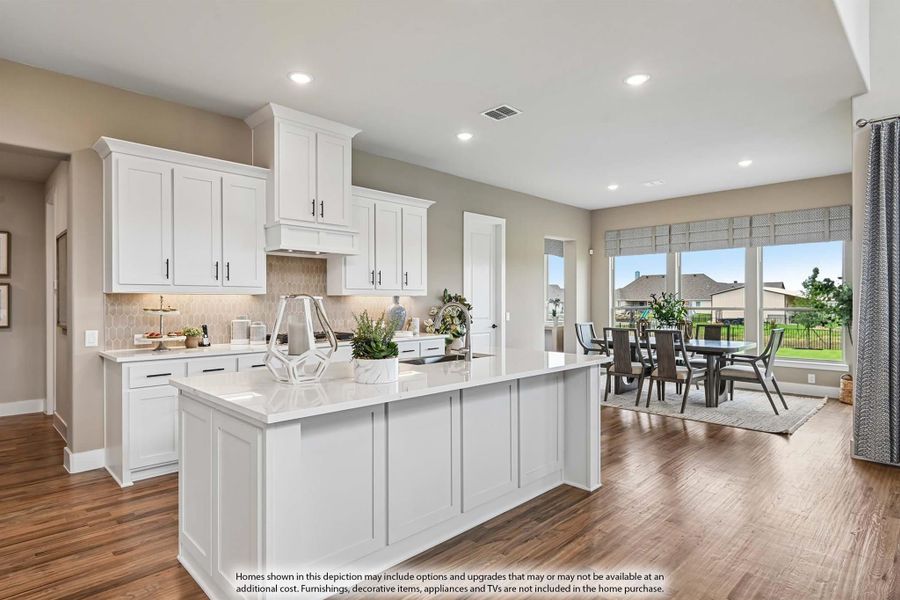 Open kitchen with white cabinets, large island, quartz countertops, and hardwood floors leading to dining area with large windows. Open kitchen with white cabinets, large island, quartz countertops, and hardwood floors leading to dining area with large windows.