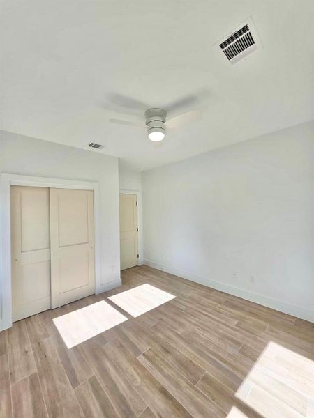 Unfurnished bedroom featuring wood finish floors, a closet, and a ceiling fan