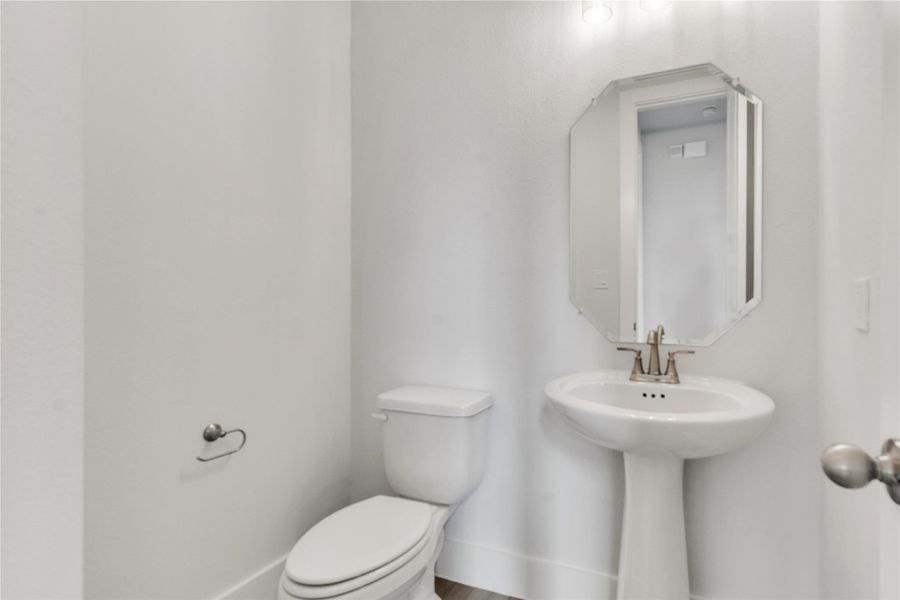 A well-appointed powder room featuring a classic pedestal sink and an elegant octagonal mirror.