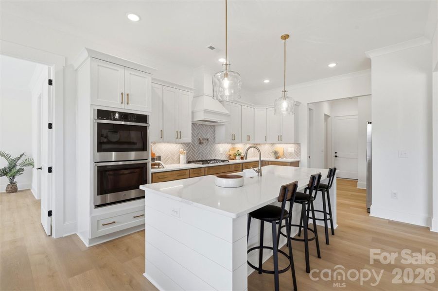 gourmet kitchen- custom  wood hood vent, porcelain farmmhouse sink, high quality quartz island, double oven, gas cooktop
