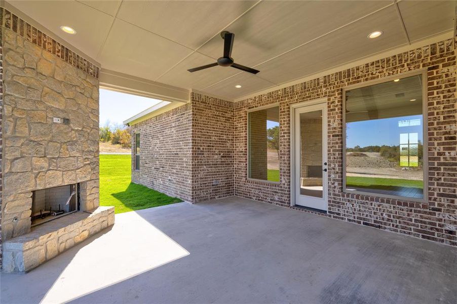 View of patio with ceiling fan and an outdoor stone fireplace