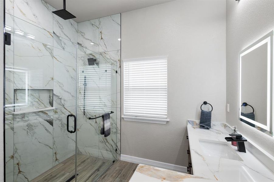 Bathroom featuring vanity and a marble finish shower