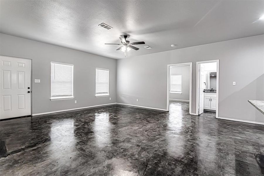 Unfurnished living room with ceiling fan and a textured ceiling