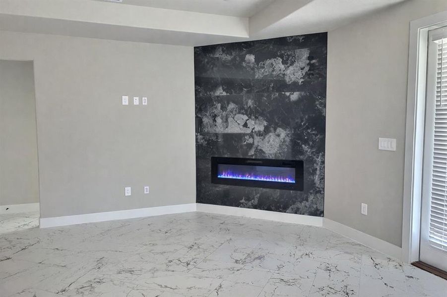 Unfurnished living room with a fireplace and light marble finish floors
