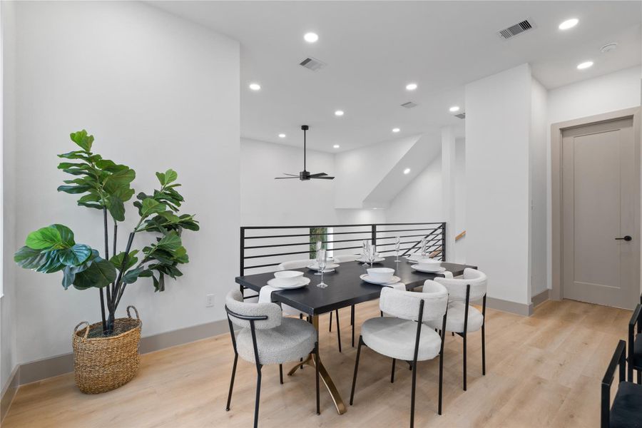 Overlooking the dramatic two-story living room, this open dining area features modern railing details, recessed lighting, and wide-plank SPC flooring—blending form and function in an architecturally distinct layout. Overlooking the dramatic two-story living room, this open dining area features modern railing details, recessed lighting, and wide-plank SPC flooring—blending form and function in an architecturally distinct layout.