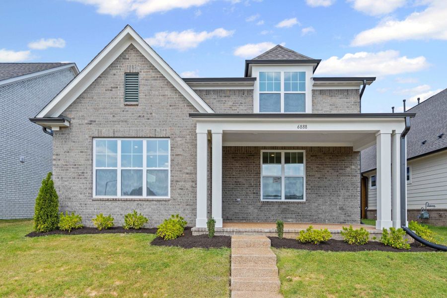 View of front facade with covered porch, brick siding, and a front yard View of front facade with covered porch, brick siding, and a front yard