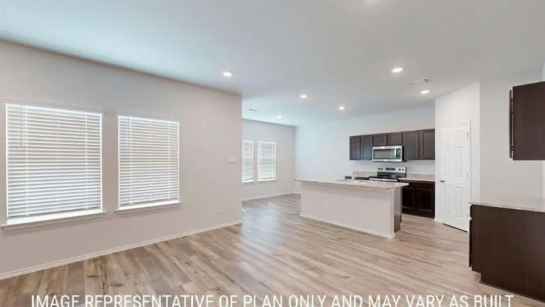Open-concept living space featuring wood-finish flooring throughout, recessed lighting, and multiple windows with blinds Open-concept living space featuring wood-finish flooring throughout, recessed lighting, and multiple windows with blinds