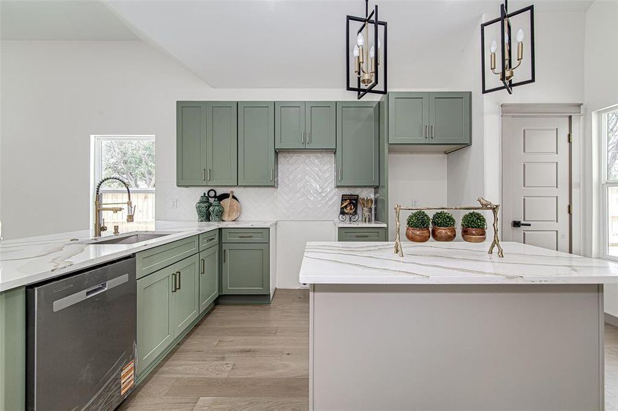 Kitchen featuring dishwasher, green cabinetry, vaulted ceiling, backsplash, and light stone countertops